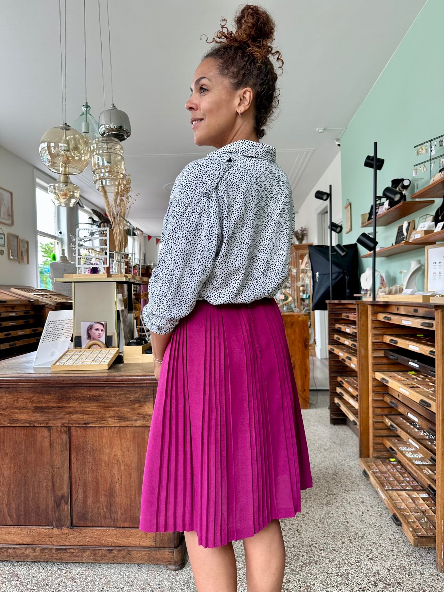 Achterkant van violet plooirok in magenta kleur met rits en knoopsluiting