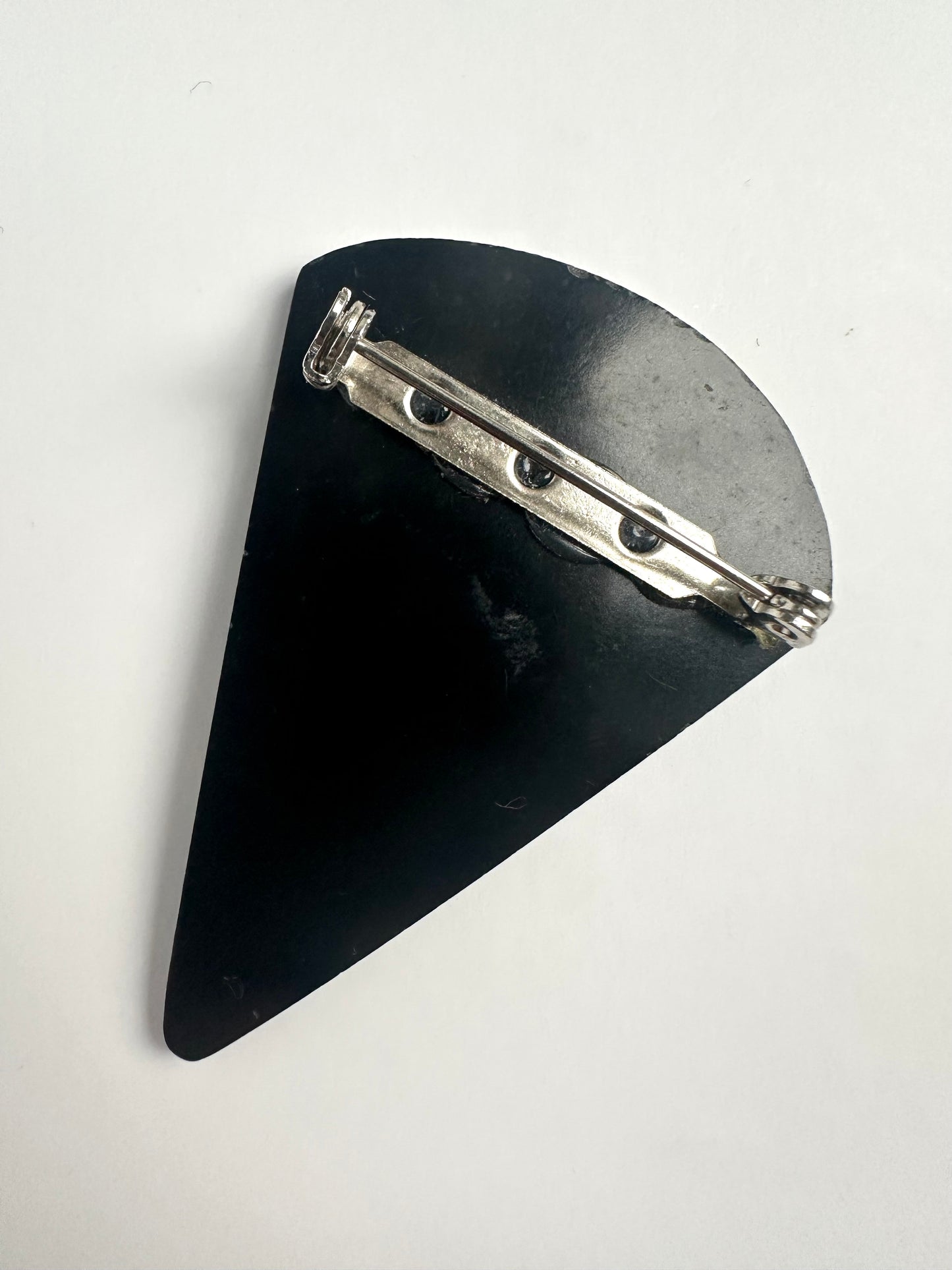 Zwarte achterkant van de driehoevormige broche