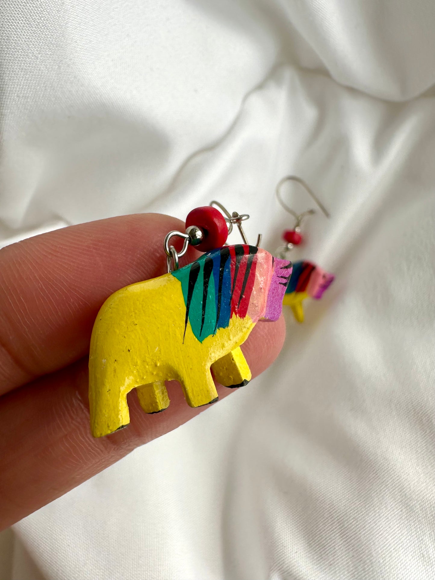 Detailfoto van nineties houten oorbellen, handbeschilderd in geel met regenboog patroon
