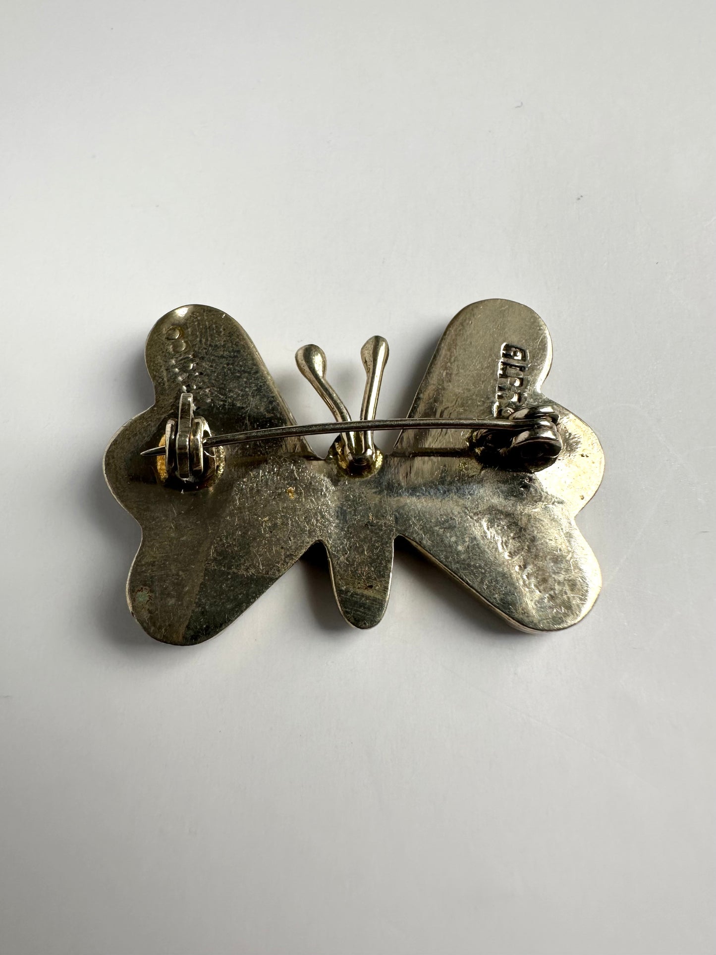 Achterkant van zilverkleurige retro vlinderbroche met alpaca inscriptie