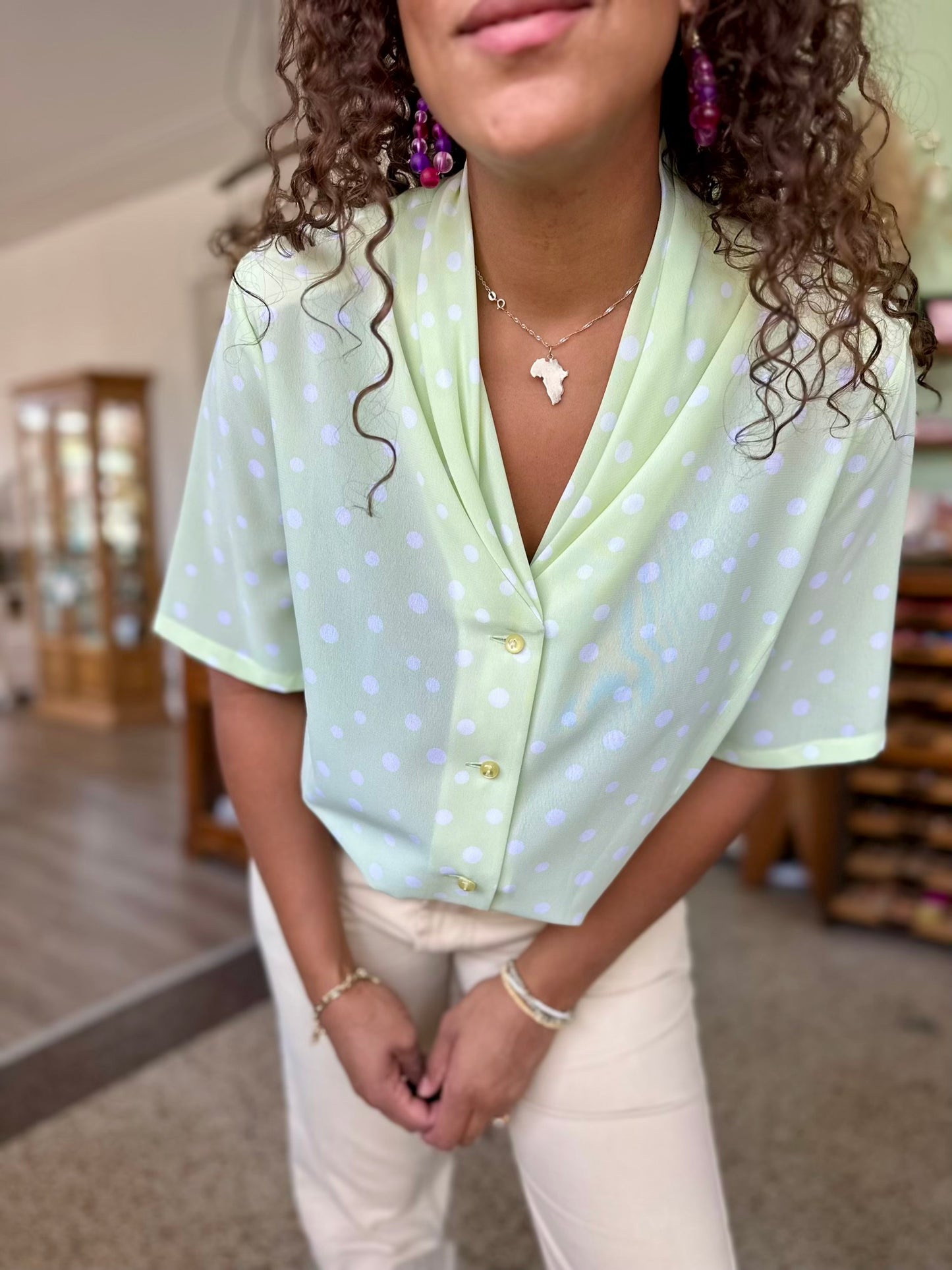 Detail van vrouwelijke vintage blouse in groen met stippenprint en elegante gouden details