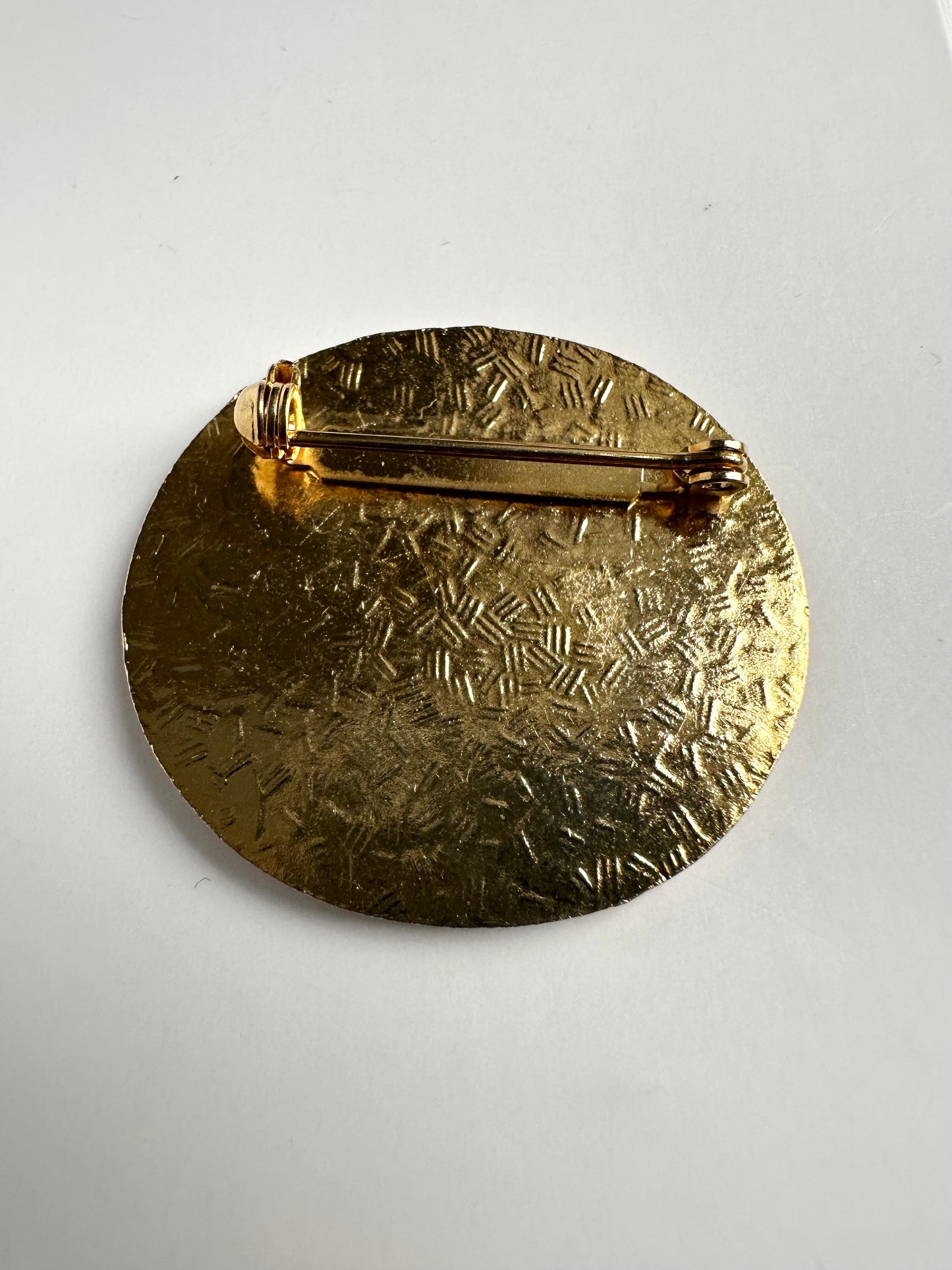 Achterkant van de cloisonne broche waarop het metaal ingekerfd is