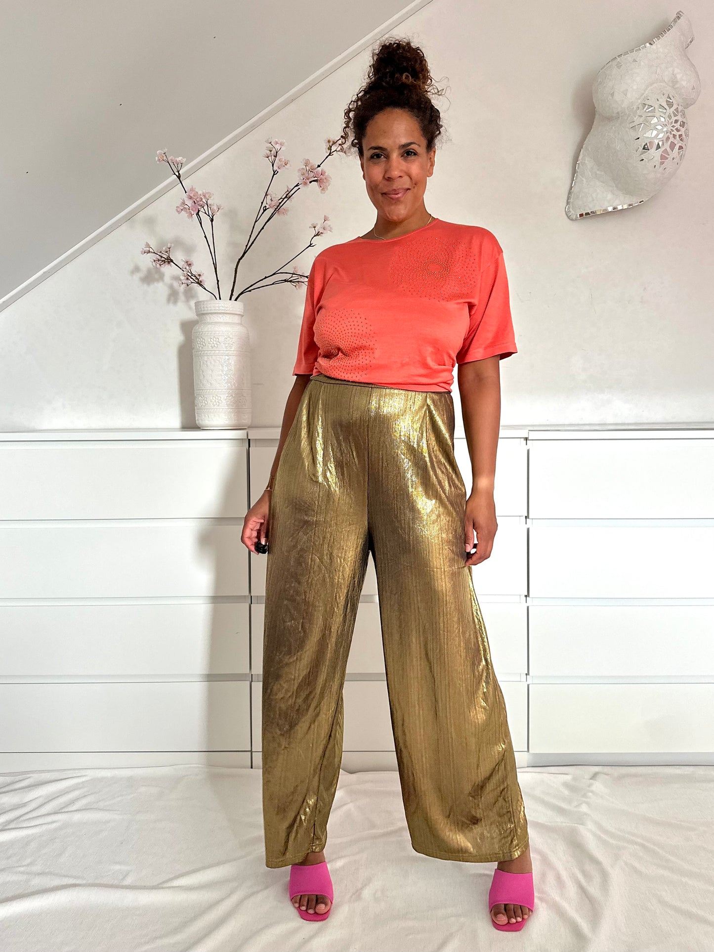 Vintage gouden jumpsuit met wijde pijpen gedragen met een koraalkleurig tshirt