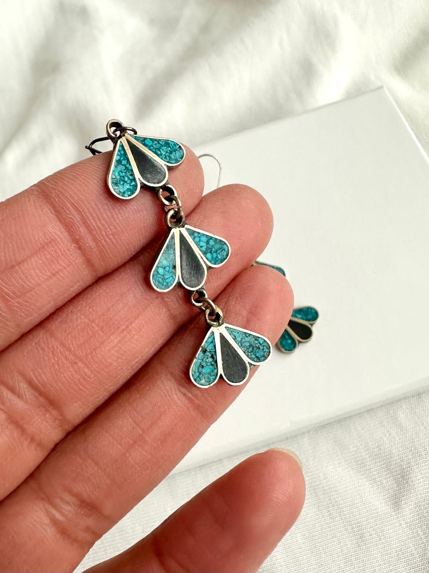 Details van de lange oorhangers in zilver, met turquoise en zwarte details