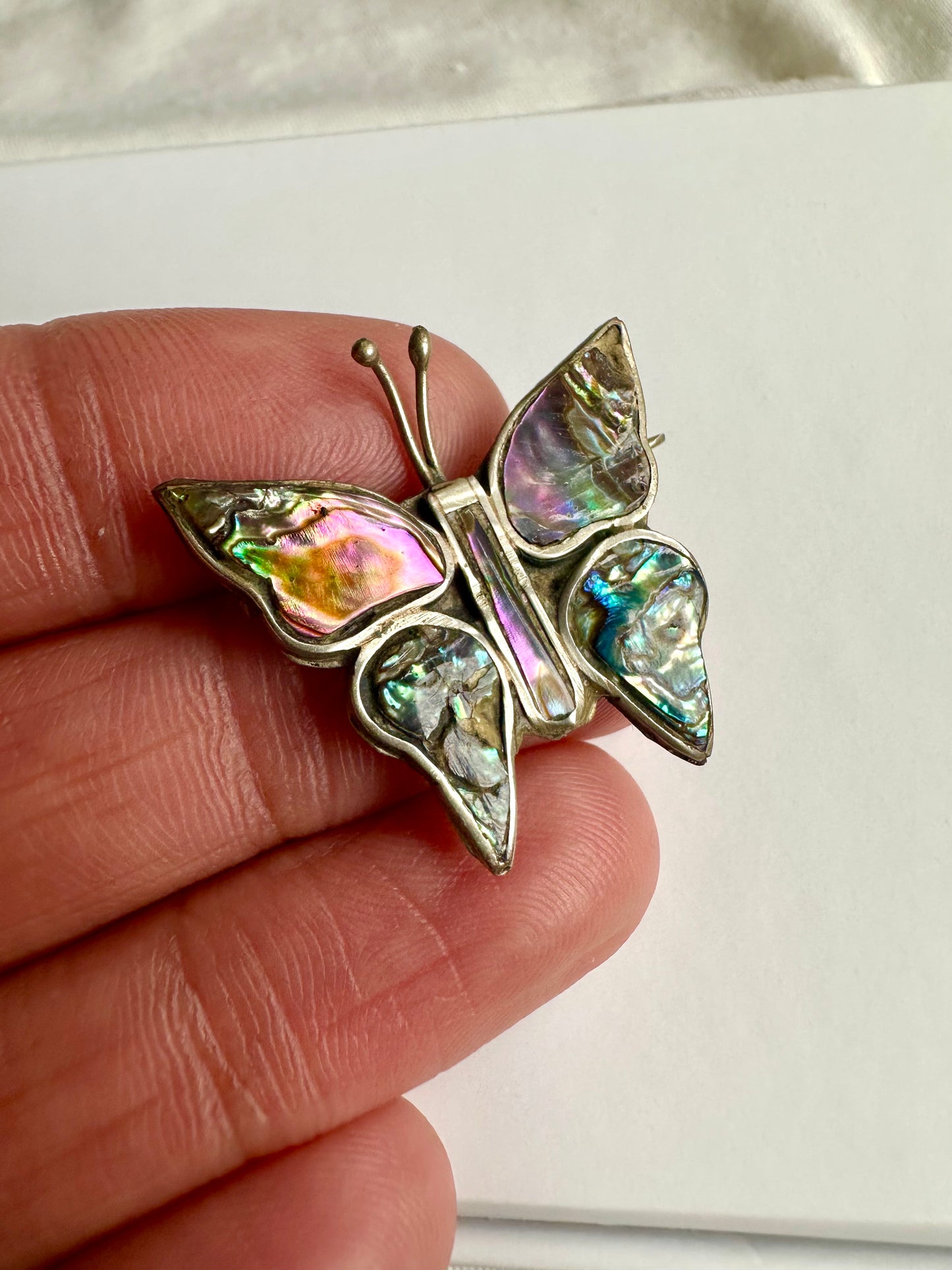 Detailfoto van de vlinderbroche, waarop de glanzende parelmoer schittering goed te zien is