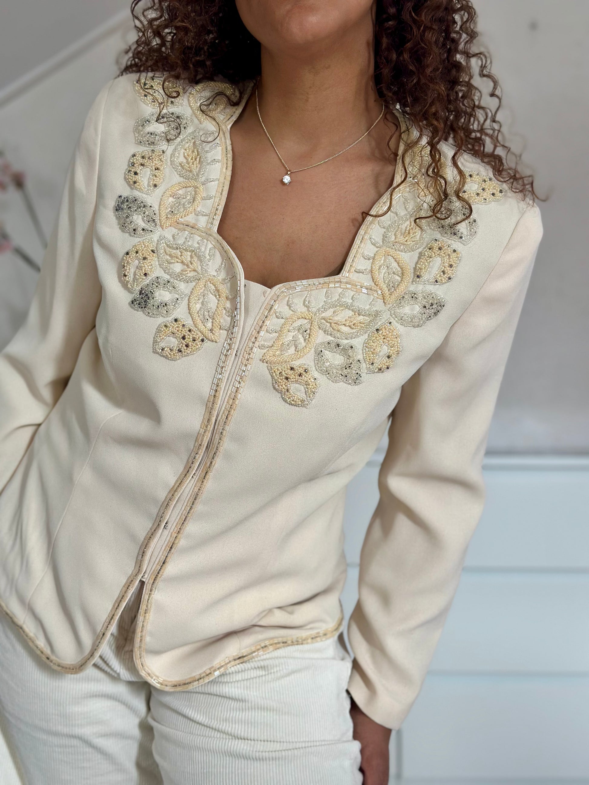 Detailfoto van vintage blazer met geborduurde bloemenapplicaties en elegante afwerking.