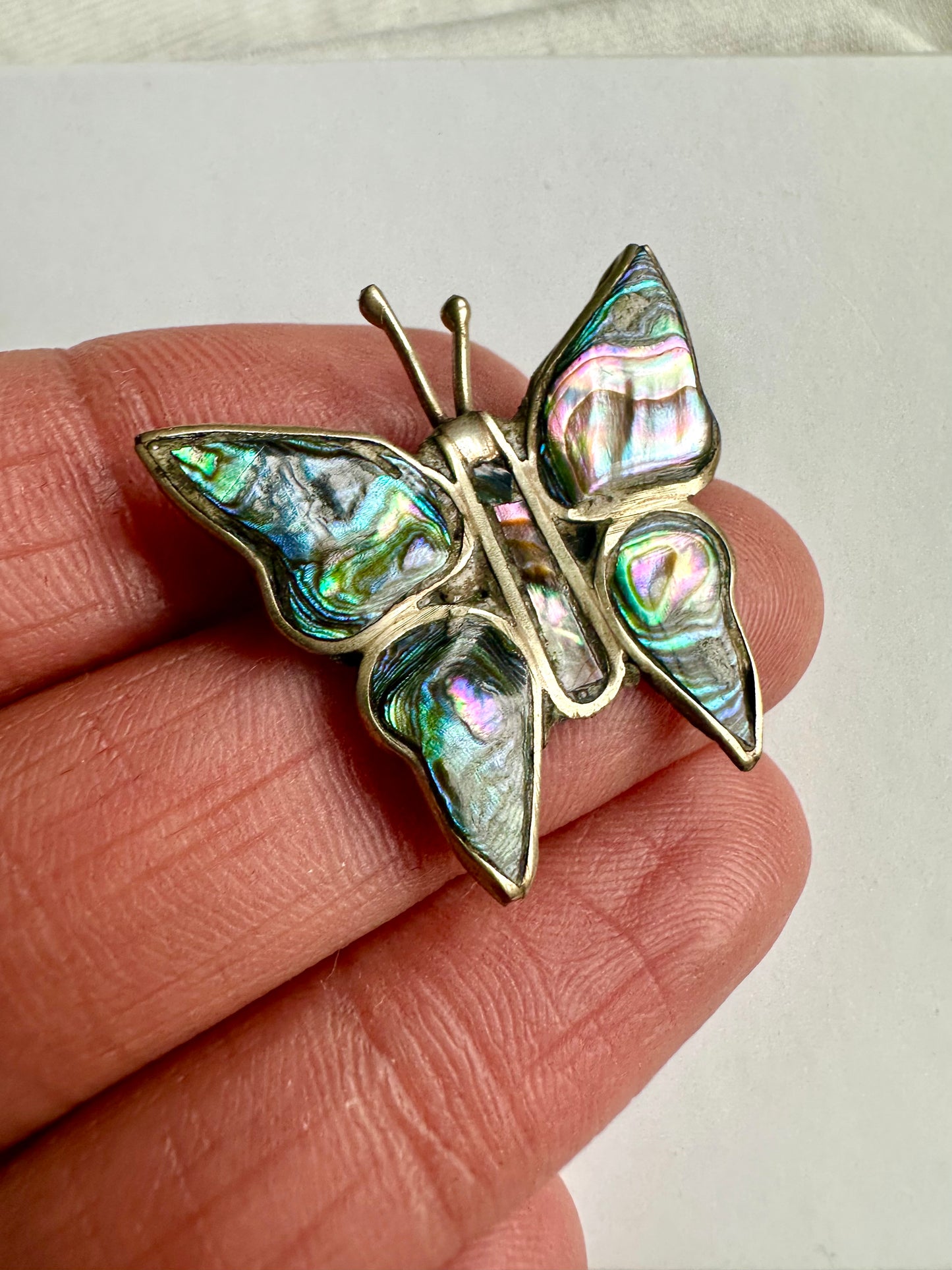 Detailshot van vlinder vormige retro broche, met glanzende parelmoeren toplaag 