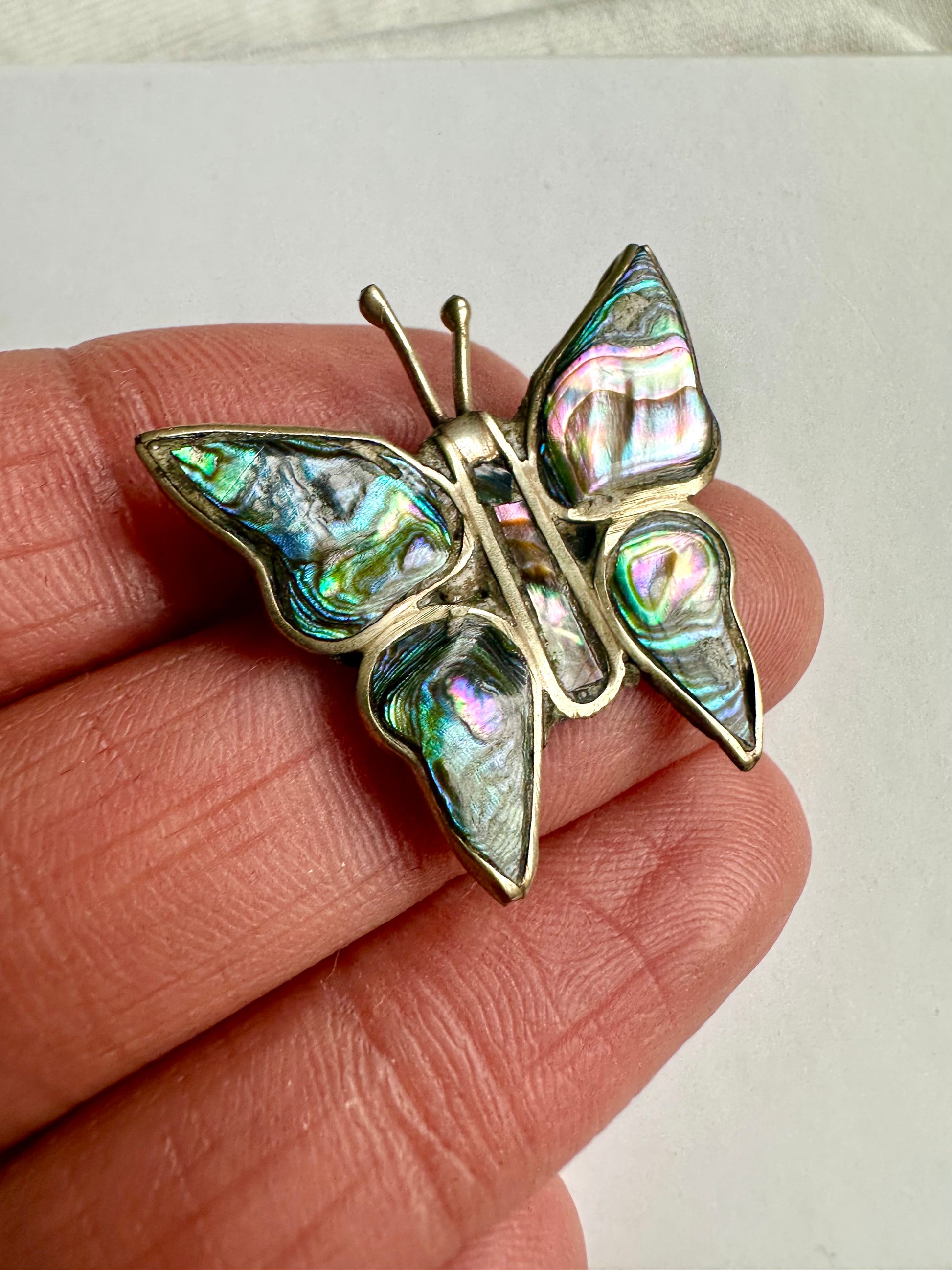 Detailshot van vlinder vormige retro broche, met glanzende parelmoeren toplaag 