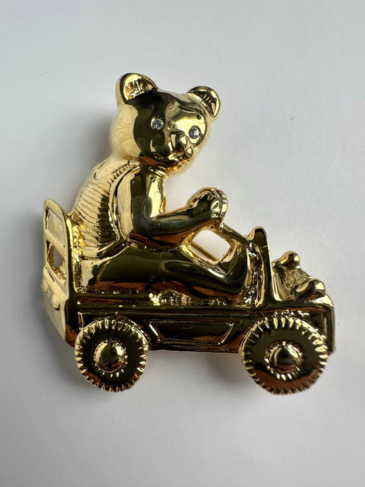 Goudkleurige vintage broche in de vorm van een beer die in een auto zit