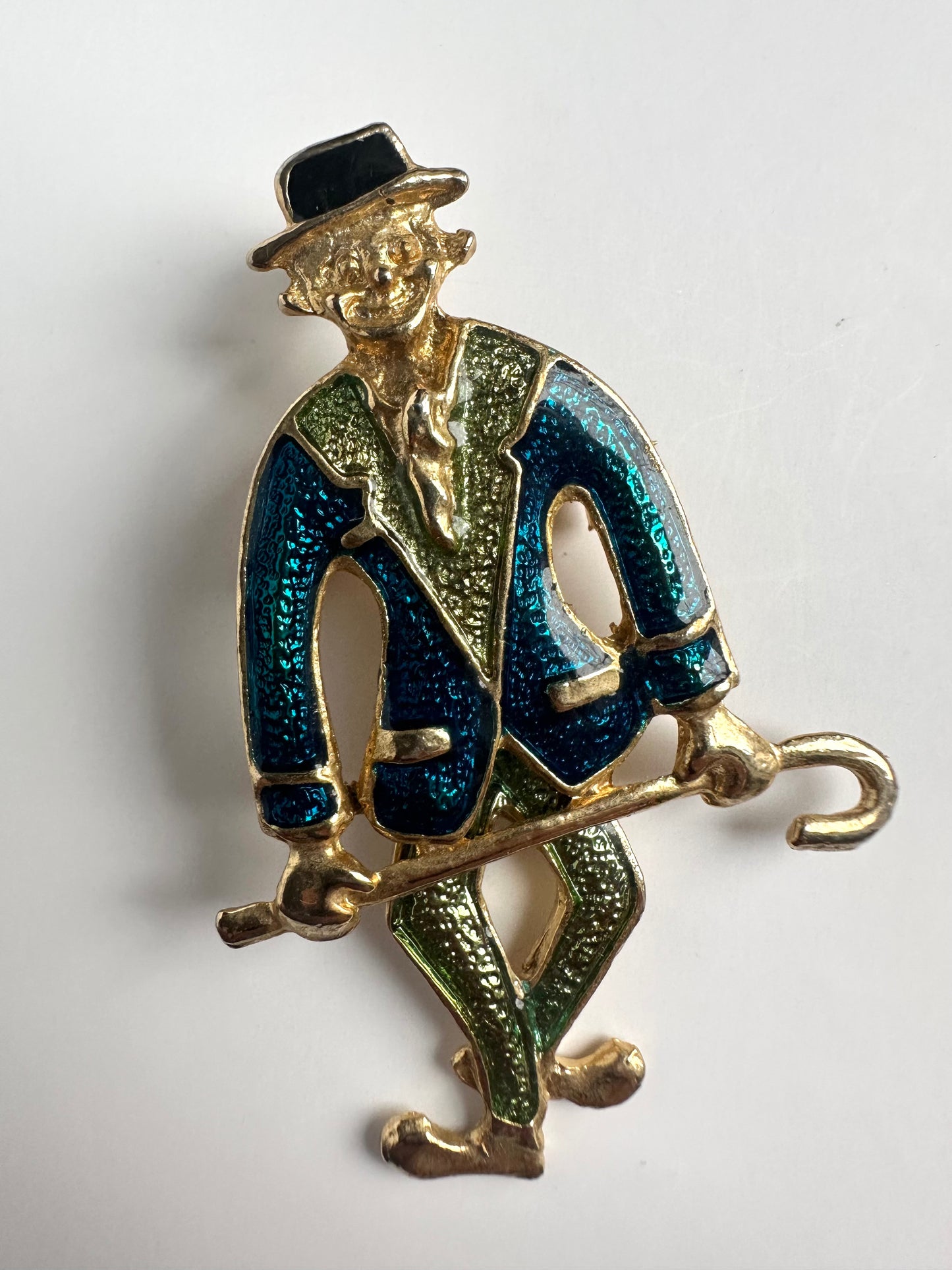 Vintage gouden broche in vorm van een clown met blauw en groene kleding en hangende benen
