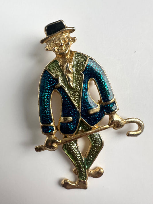 Vintage gouden broche in vorm van een clown met blauw en groene kleding en hangende benen