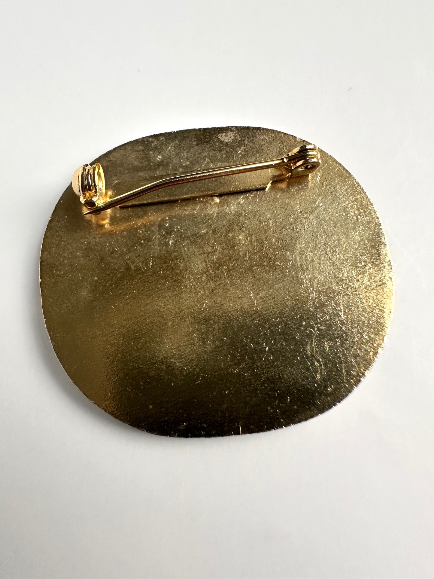 Achterkant van de vergulde ronde vintage broche 