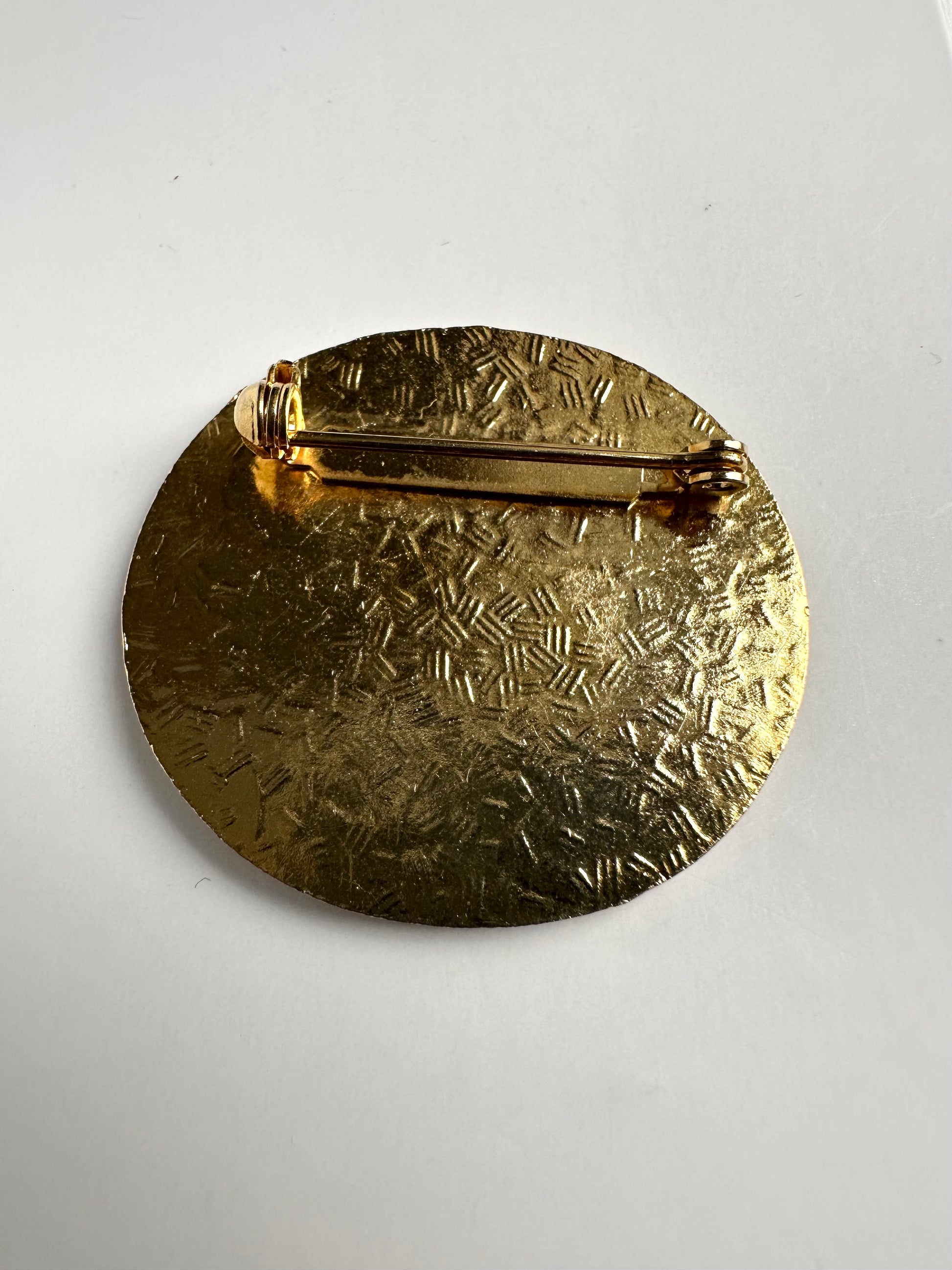 Achterkant van de cloisonne broche waarop het metaal ingekerfd is