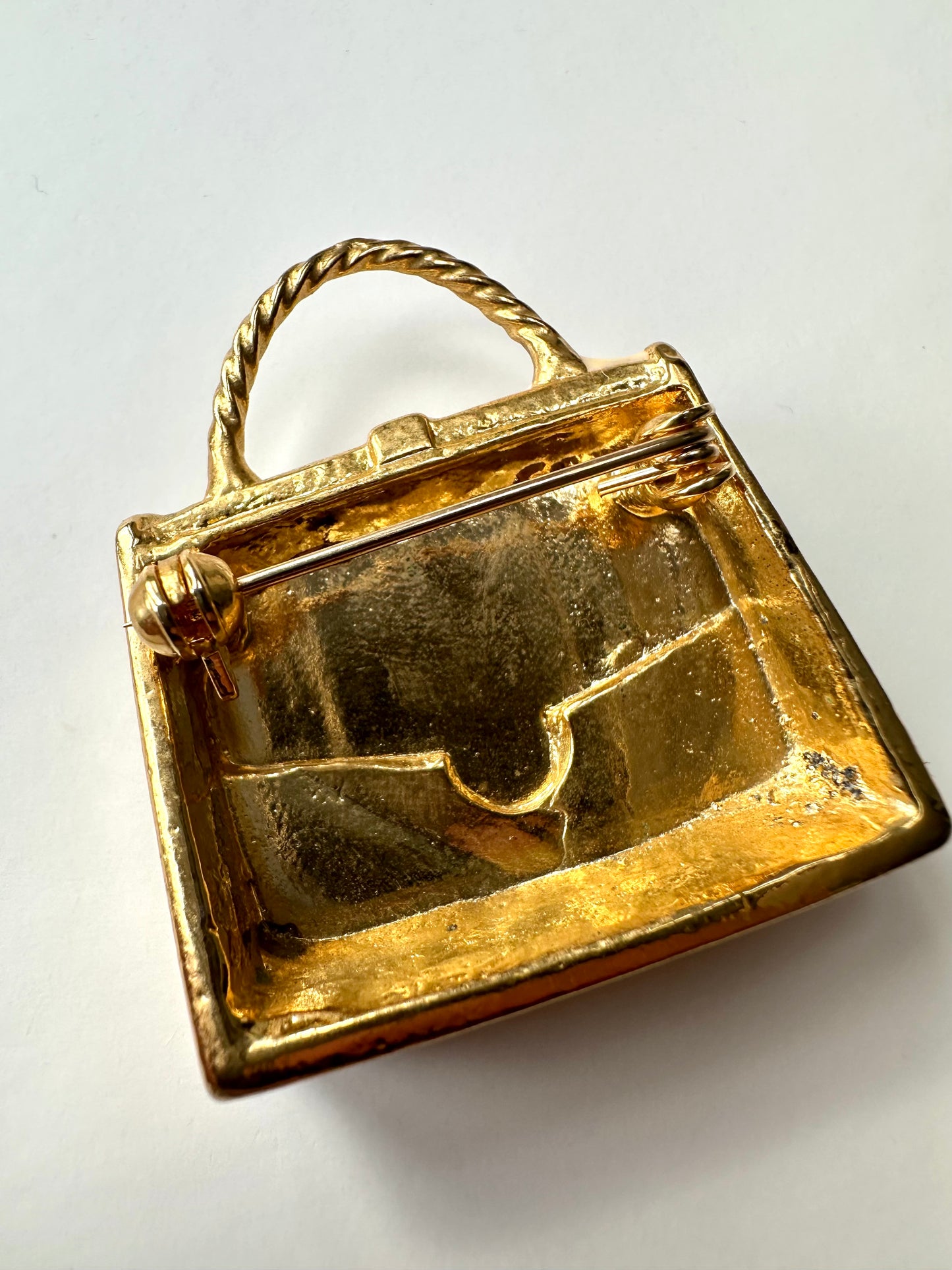 Achterkant van vintage broche in de vorm van een tas, met vergulde binnenkant zichtbaar 