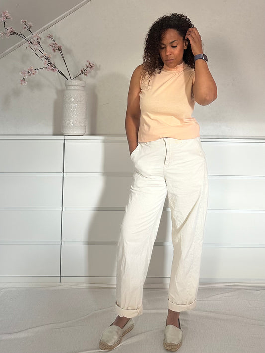 Vintage mouwloze top in zachte zalmkleur, gecombineerd met een witte broek.