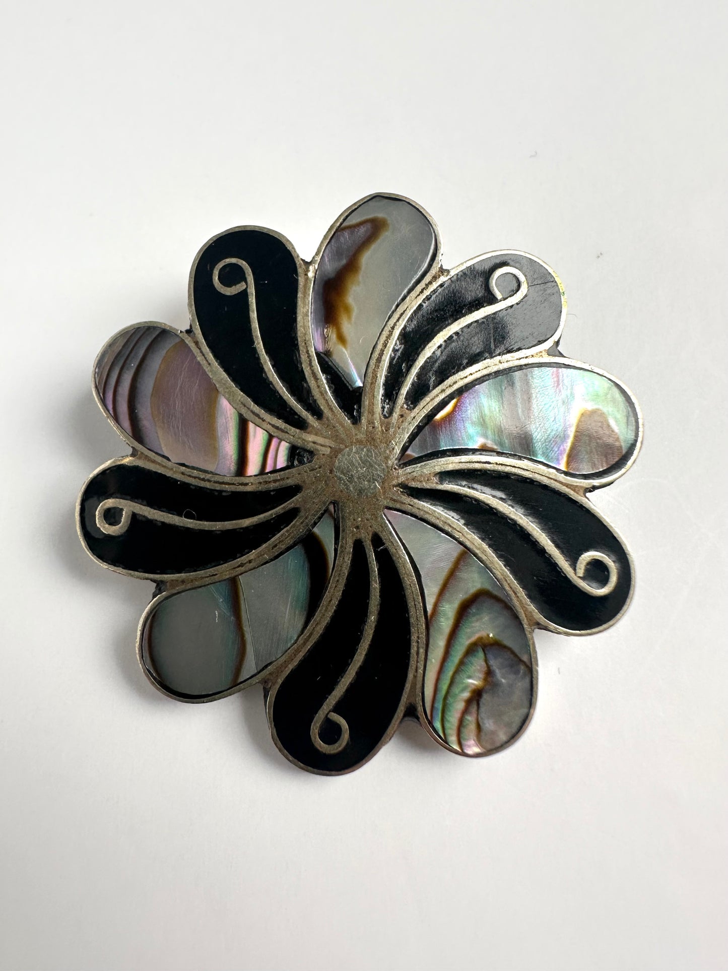 Vintage zilverkleurige broche in swirl vorm met parelmoer en albalone schelp