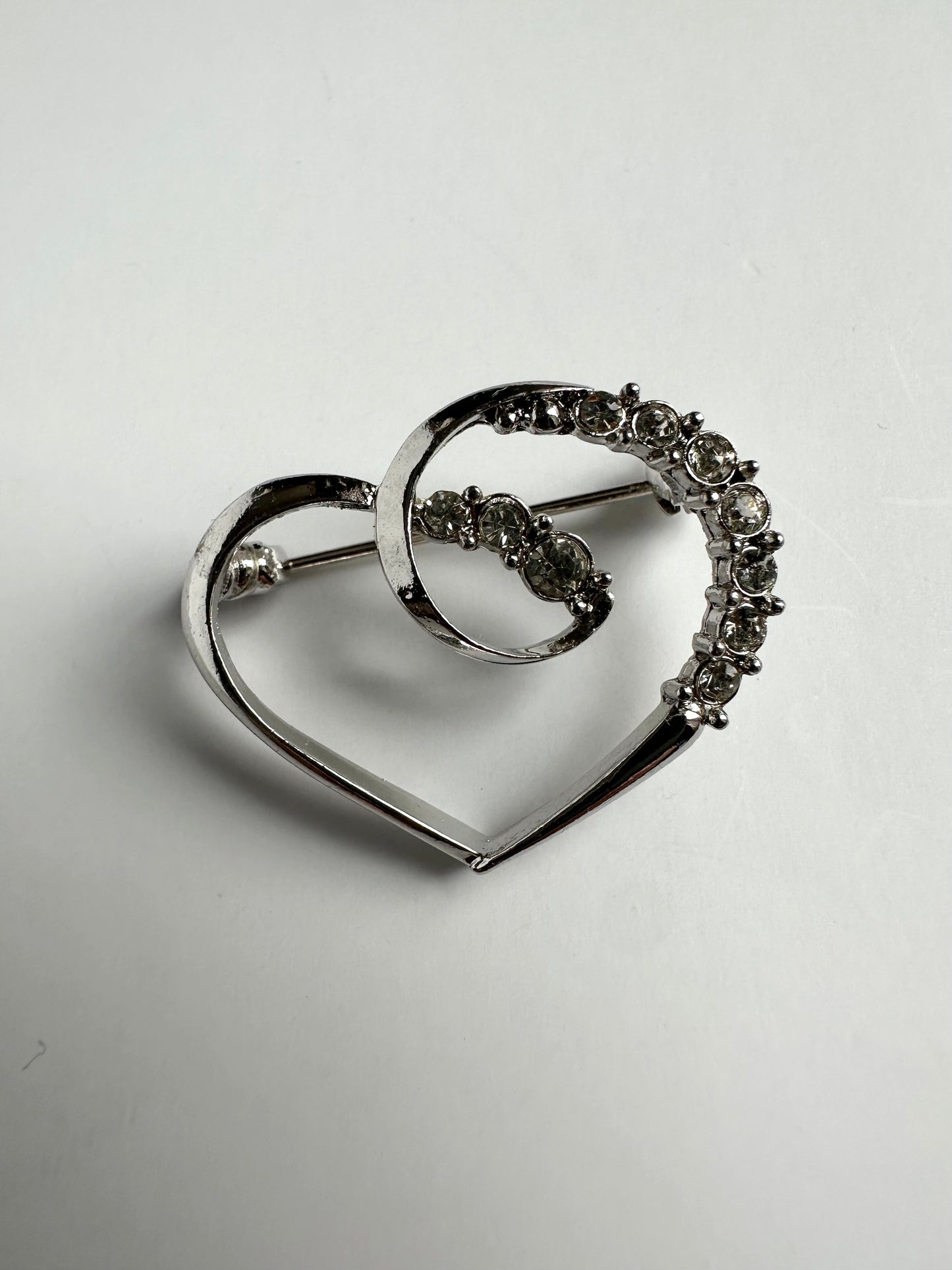 Vintage zilverkleurige broche in de vorm van een hart met strass steentjes 