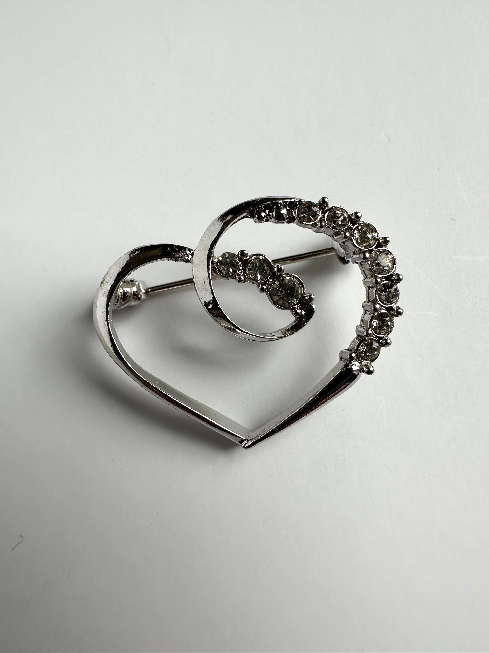 Vintage zilverkleurige broche in de vorm van een hart met strass steentjes 