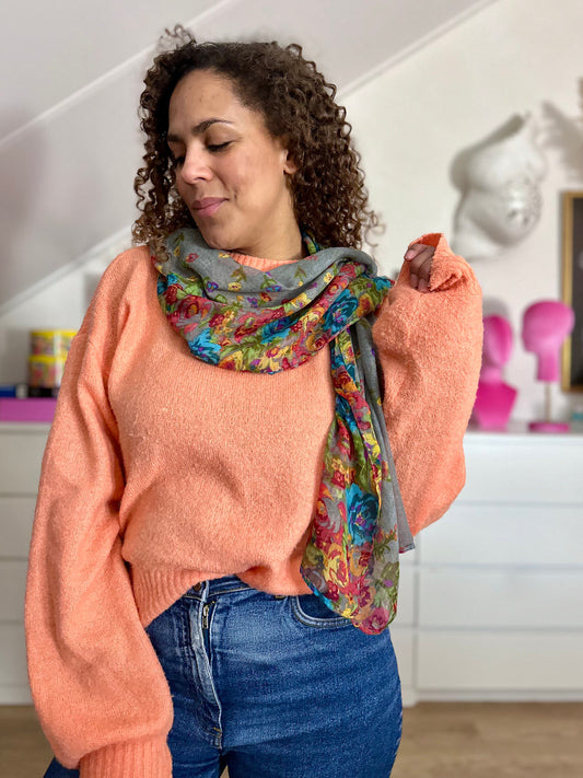 Grijze rechthoekige sjaal met bloemen bewerk, hier nonchalant rond de schouders gedrapeerd 