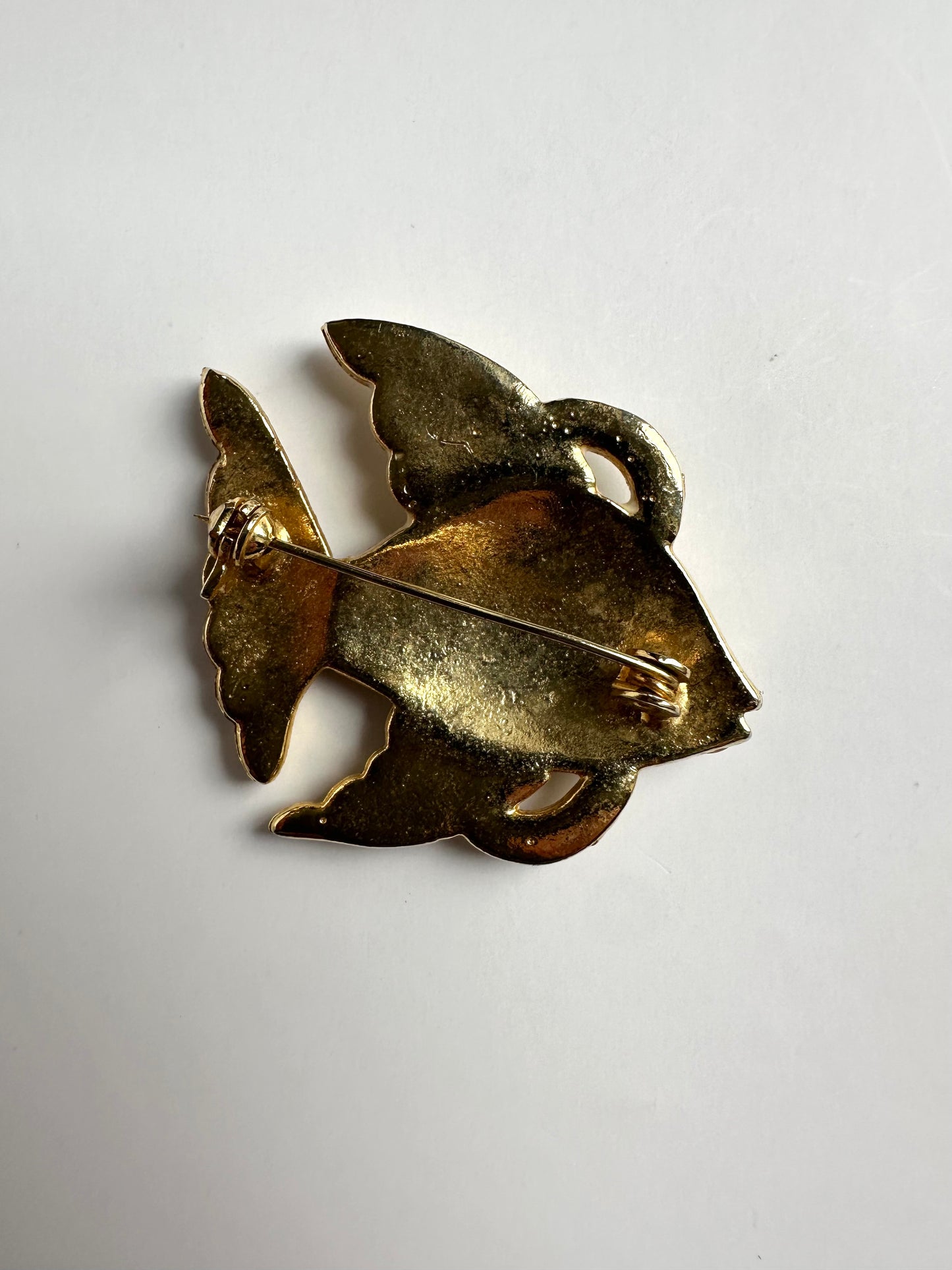 Achterkant van een goudkleurige retro broche in de vorm van een vis 