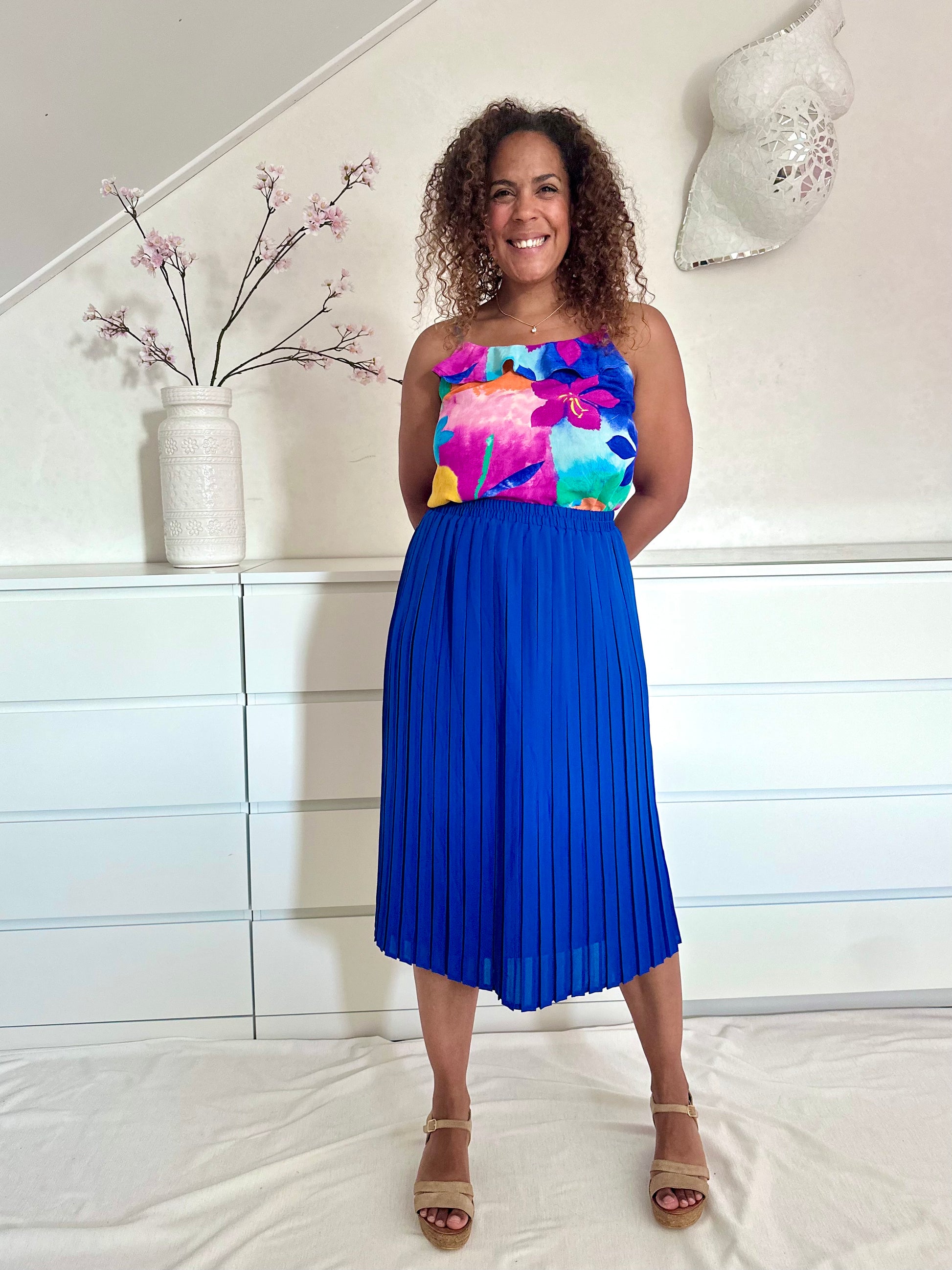 vintage plooirok in blauw met hoge taille en sierlijke plooien, gedragen met felgekleurde top