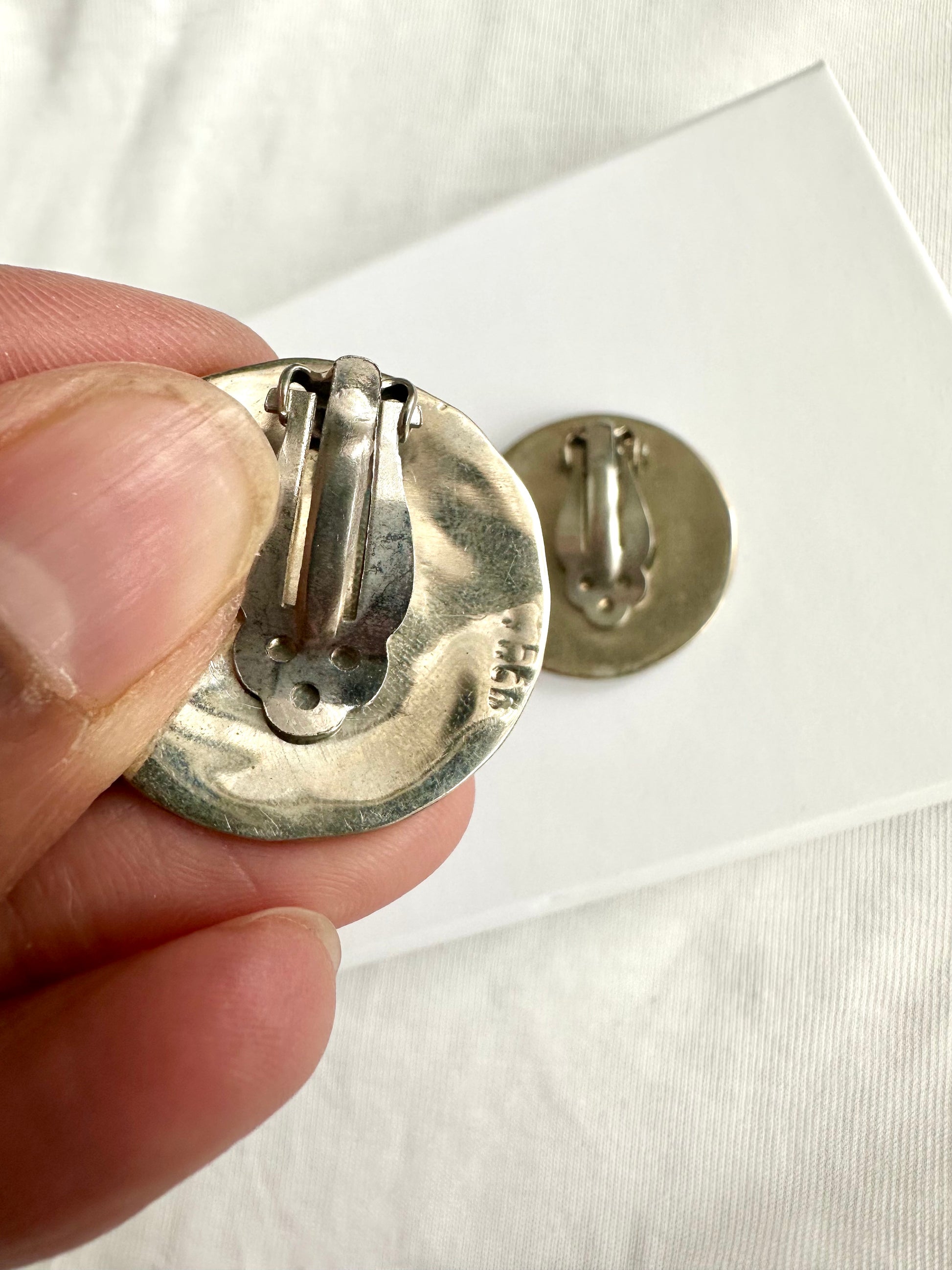 Detailfoto van retro clip-on oorbellen met zilvermerkje